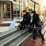 Go down a flight of stairs with a wheelchair with assistance